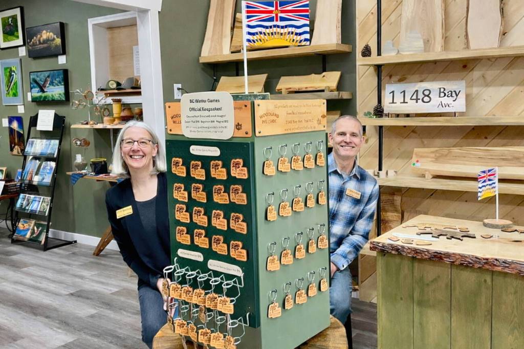 Woodland Hillside owners Melissa Woodward and Ghislain Avoine showcase official Trail-Rossland 2026 BC Winter Games keepsakes at their Bay Avenue shop. Thirty per cent of sales will support the local host society. (Sheri Regnier/Trail Times)